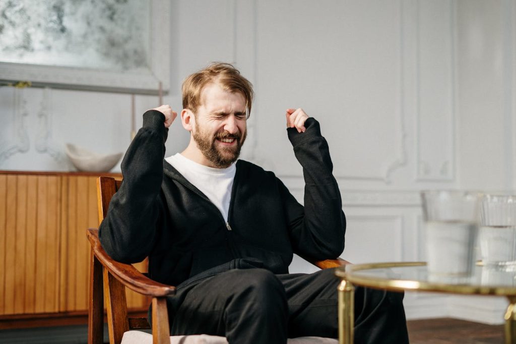 A bearded man expressing emotional distress in a modern interior setting, seeking mental health support.